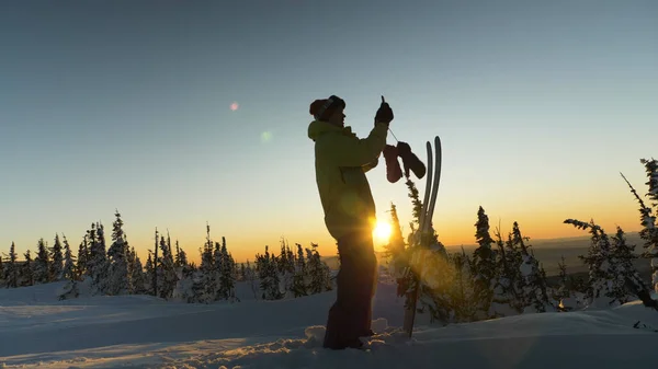 Skicklig skidåkare håller smartphone i handen och foton solnedgång — Stockfoto