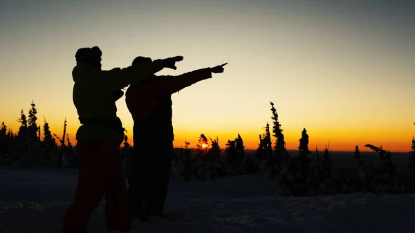 Människor silhuetter beundrar bildens solnedgång och höja händerna — Stockfoto
