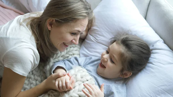 Όμορφη μητέρα λέει παραμύθι στην κόρη κάτω από κουβέρτα — Φωτογραφία Αρχείου