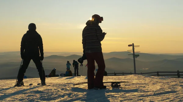 Actieve toerist met skies snowboards silhouetten bij zonsondergang — Stockfoto