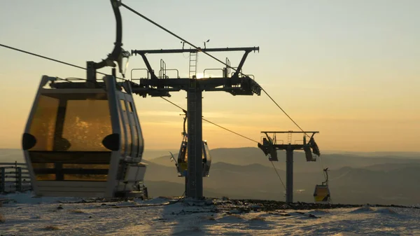 Moderne Skiliftkabinen bewegen sich über weißen Schnee gegen Bergkuppen — Stockfoto