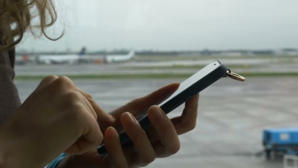 Menina mãos surfs internet no celular contra aeródromo no aeroporto — Vídeo de Stock