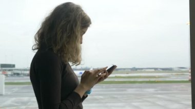 Havaalanı terminalinde kadın cep telefonu kullanıyor.