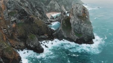 Okyanus kıyısındaki çıplak kayalıklar resimli dalgalarla yıkanmış.