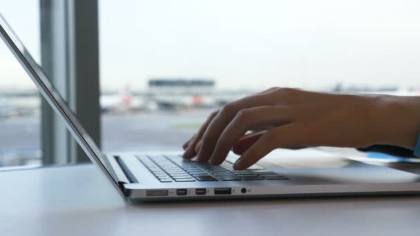 Tipos de dama en el teclado del ordenador portátil en la cafetería del aeropuerto vista cercana — Vídeo de stock