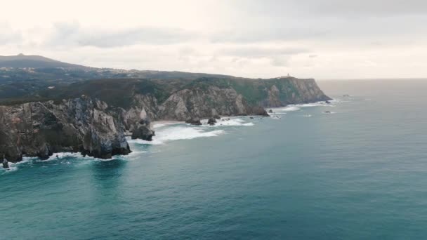 Rotsachtige kust door pittoreske oceaan met golven op winderige dag — Stockvideo