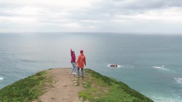 Homem e mulher se alegram ao chegar a um lugar deslumbrante acima do oceano — Vídeo de Stock