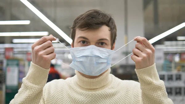 Человек в супермаркете почувствовал облегчение, сняв медицинскую маску. Пандемия коронавируса закончилась. Жизнь прекрасна. . — стоковое фото