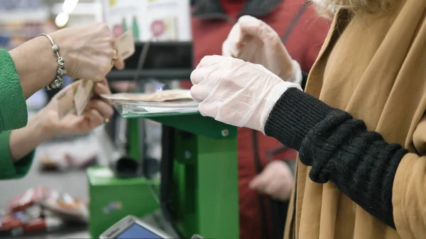 Жінка в супермаркеті підбирає зміни після покупки в гумових захисних рукавичках. Заходи безпеки проти коронавірусної інфекції . — стокове фото