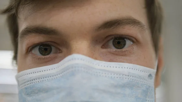 Врач в медицинской маске смотрит на камеру очень близко, пандемический ковид-19 — стоковое фото