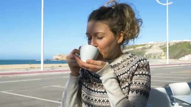 Mujer joven sostiene taza blanca bebe té contra la unidad del océano — Vídeo de stock