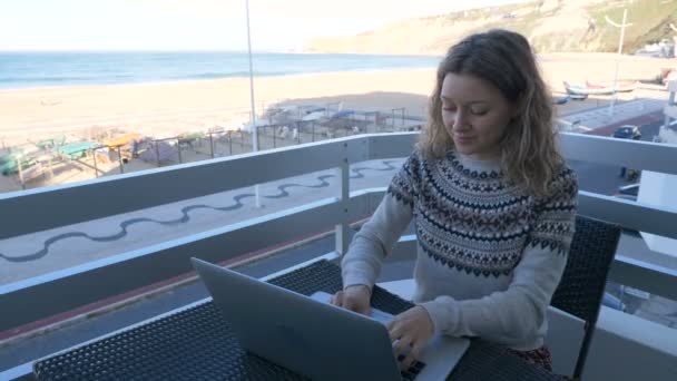 Γυναίκα με όμορφο χαμόγελο κάθεται στο μπαλκόνι με φορητό υπολογιστή εργασίας — Αρχείο Βίντεο