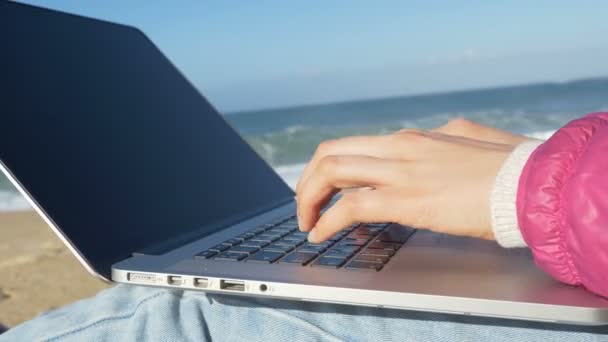 Ноутбук лежит на коленях девочка пальцы типа на клавиатуре у океана — стоковое видео