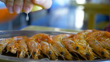 Tabakta kırmızı karides ve taze limon suyu sıkıyor.