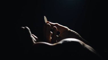 Kirli ellere düşen Euro sikkeleri karanlıkta kara arka planda para sayar.