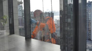 Endüstriyel tırmanışçılar ön cepheyi lastik eldivenlerle yıkarlar. Koronavirüs salgınından korunma. Virüs ve pisliğe karşı antiseptik ile yüzey tedavisi.