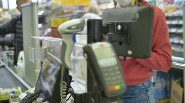 Kadın süpermarketteki kasaya lastik eldivenle ödeme yapıyor. Koronavirüsten korunma.