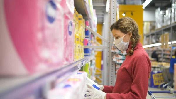 Meisje in handschoenen en medisch masker kopen rollen wc-papier, pandemische coronavirus supermarkt beschermende apparatuur — Stockfoto