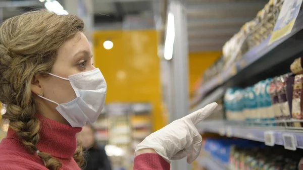 Kvinde i maske og gummihandsker vælger mad i supermarkedet close-up, beskyttelse coronavirus på offentligt sted - Stock-foto