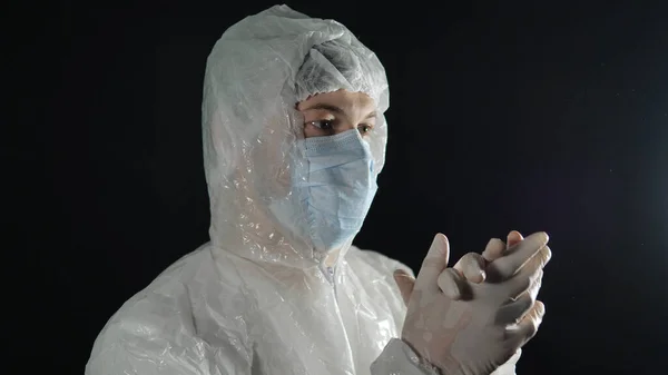 Доктор у медичній масці та захисних костюмах в гумових рукавичках на темному тлі. Підтримка лікарів у боротьбі з пандемією коронавірусу . — стокове фото