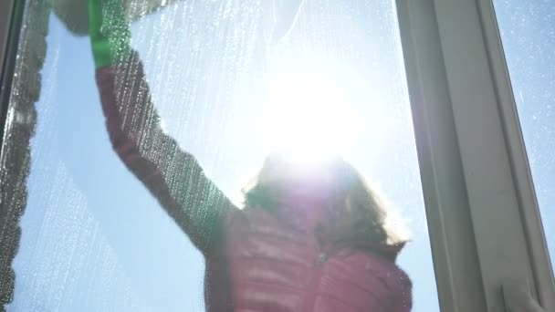 Meisje wassen raam op balkon doekjes wasmiddel met rubberen stok — Stockvideo