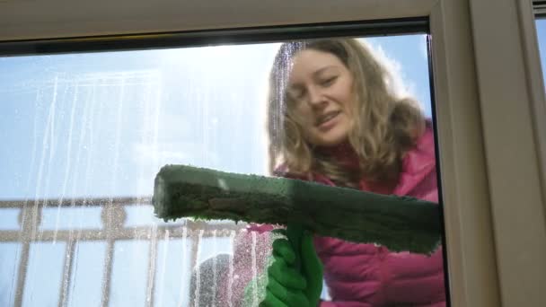 Femme heureuse dans des gants en caoutchouc lave fenêtre sale avec manteau de fourrure à l'aide de détergent à l'extérieur — Video