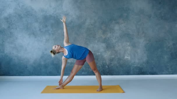 Yoga instructeur doen driehoek pose, stretching laterale spieren van het lichaam, arm omhoog kantelen, slow motion — Stockvideo
