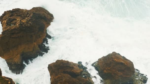 Vuelo aéreo sobre roturas de olas en piedra en la parte superior del océano vista cámara lenta. — Vídeos de Stock