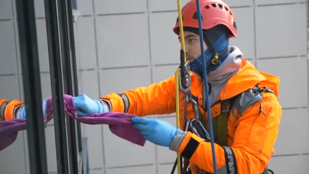 Průmyslový horolezec v přilbových ubrouscích zůstává speciální hadr a klouže po laně se spouští — Stock video