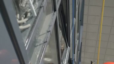 Turuncu elbiseli endüstriyel tırmanıcı, lateks eldiven salgını sırasında camları siler.