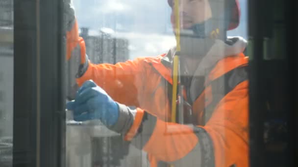 工业登山者穿着橙色连衣裙,慢动作地在安全装备中擦拭窗户.从灰尘和泥土中清洗窗户. — 图库视频影像