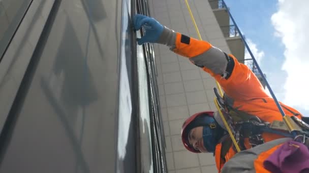 Professionele klimmer in helm wast ramen met bontjas op grote hoogte, slow motion — Stockvideo