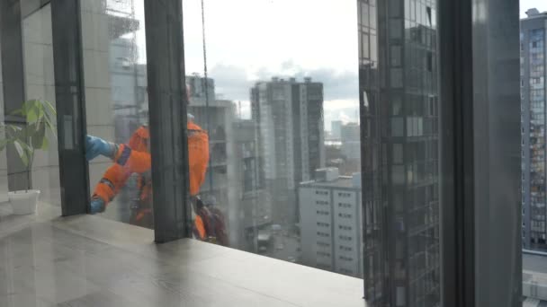 Industrial climber washes the facade glazing in rubber gloves. Protection from the coronavirus pandemic. Surface treatment with an antiseptic against viruses and dirt. — Stock Video