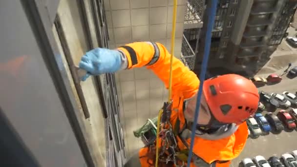 Professioneel uitgeruste industriële klimmer in helm en handschoenen wast ramen met een dekvloer — Stockvideo