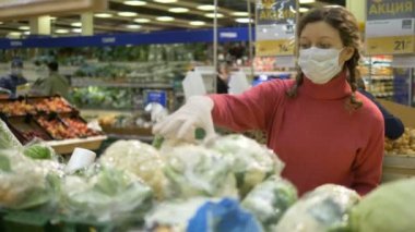 Maskeli ve eldivenli kadın süpermarketten taze karnabahar seçiyor. Coronavirus covid-19 karantinası.