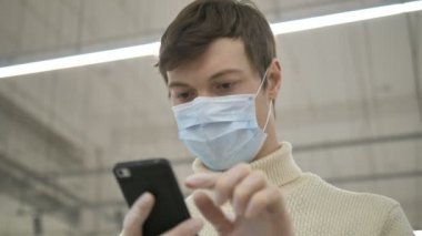 Adam koruyucu maske lastik eldivenler akıllı telefon iletişimi kullanıyor. Süpermarkette çalışıyor.