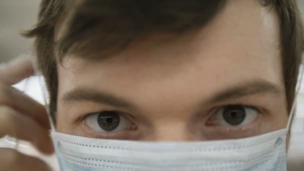 Uomo indossa maschera medica guardando la fotocamera estremamente primo piano, protezione contro il coronovirus — Video Stock