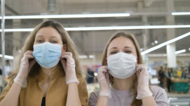 Kadın arkadaşlar sağlık maskelerini çıkartıp süpermarkette birbirlerine sarılmaktan mutlu olurlar. Koronavirüs salgını sona erdi..
