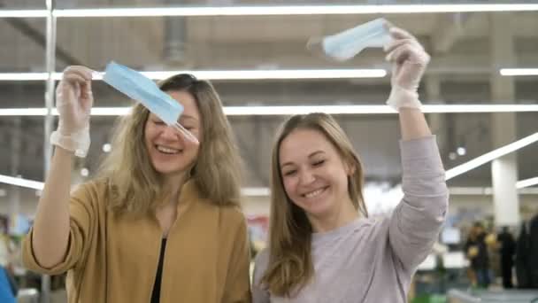 La pandémie de coronavirus est terminée. Deux petites amies heureuses ont enlevé les masques médicaux et les ont jetés, riant . — Video