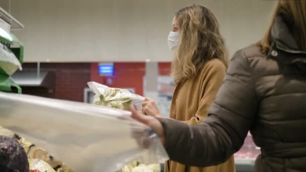 医療用マスクの女性はスーパーでカリフラワーを買う — ストック動画