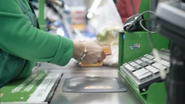 Süpermarketteki kasiyer malları yumrukluyor, yakın plan.