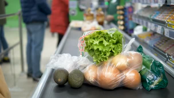 La fille à la caisse dans le supermarché répand des aliments dans des gants de caoutchouc sur la bande de direction. Protection contre les infections à coronavirus . — Video