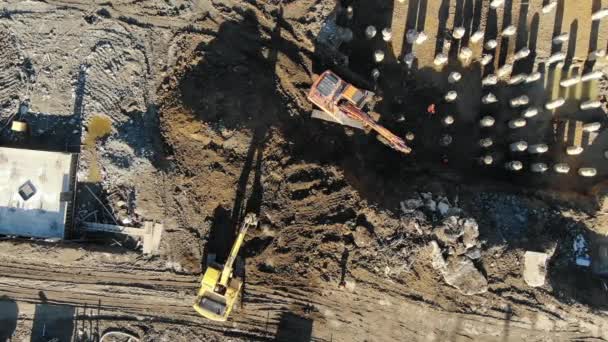 Aerial top view excavators digging ground pit for pouring foundation and laying concrete piles — Stock Video