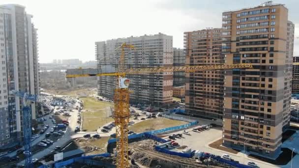 Letecký stavební jeřáb na pozadí obytných výškových budov za slunečného dne — Stock video