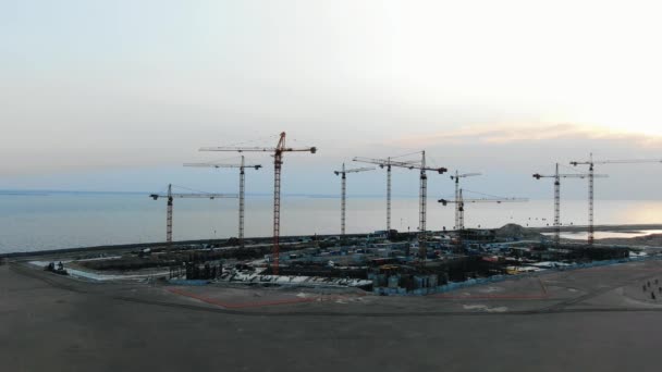 Construction site at the basement stage, cranes stand against beautiful sunset air span on bay — Stock Video