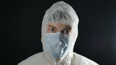 Koruyucu giysili doktor ve maskeli alkış, koronavirüs salgını covid-19 kameraya bakıyor.