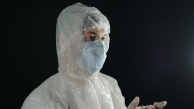 Tıbbi maskeli ve koruyucu giysili doktor siyah arka planda lastik eldivenlerle alkışlıyor. Coronavirus salgınıyla mücadelede doktorlara destek.