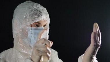 Doktor antiseptiğe tıklıyor ve eldivenleri tutuyor, sinek sıçratıyor, koronavirüs salgınından korunuyor ve tedavi oluyor.