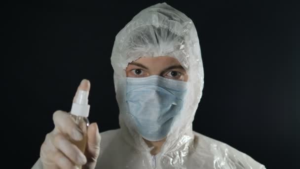 Disinfection and hygiene treatment from coronavirus doctor in white suit presses antiseptic and spray flies to camera — Stock Video