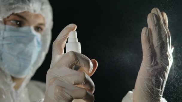 Paramedis dengan topeng medis dan baju pelindung merawat tangannya dengan antiseptik. Pandemi Coronavirus. — Stok Video
